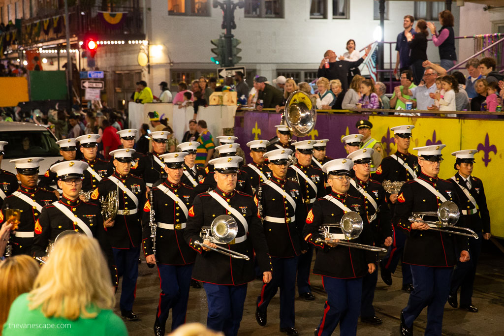 An orchestra marches down the street of New Orleans, people cheering all around.
