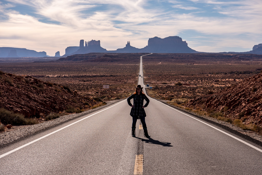 Agnes Stabinska, the author, is standing in cowboy boots and hat at the Forrest Gump Point on the Highway 163 on the way to Monument Valley.