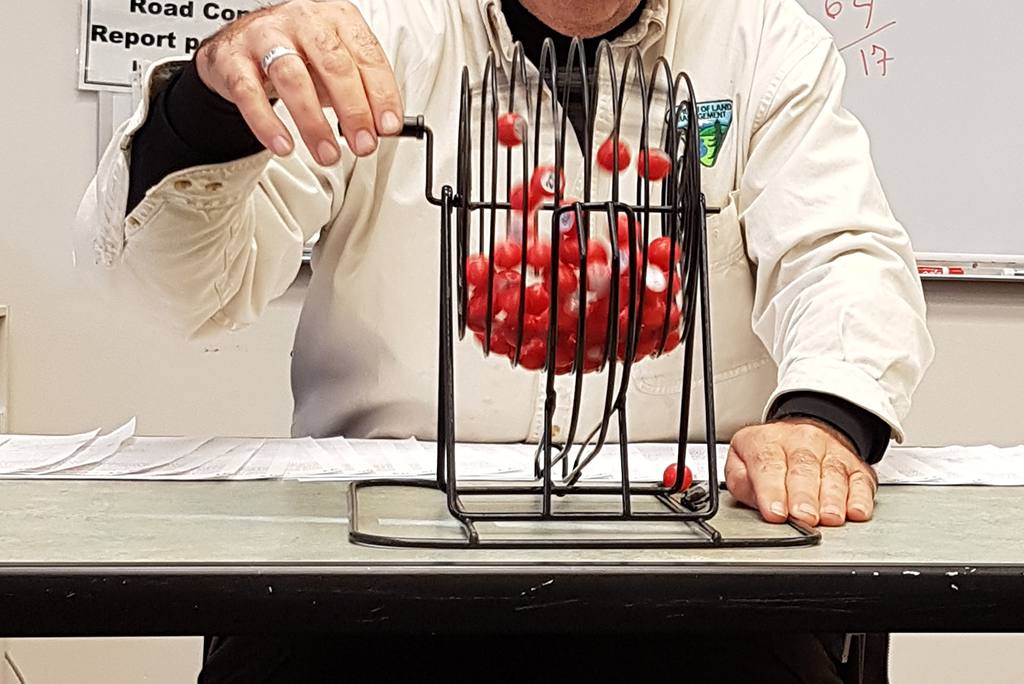 The old Wave lottery in Kanab: the ranger draws lots: he spins red plastic balls with numbers in a container.