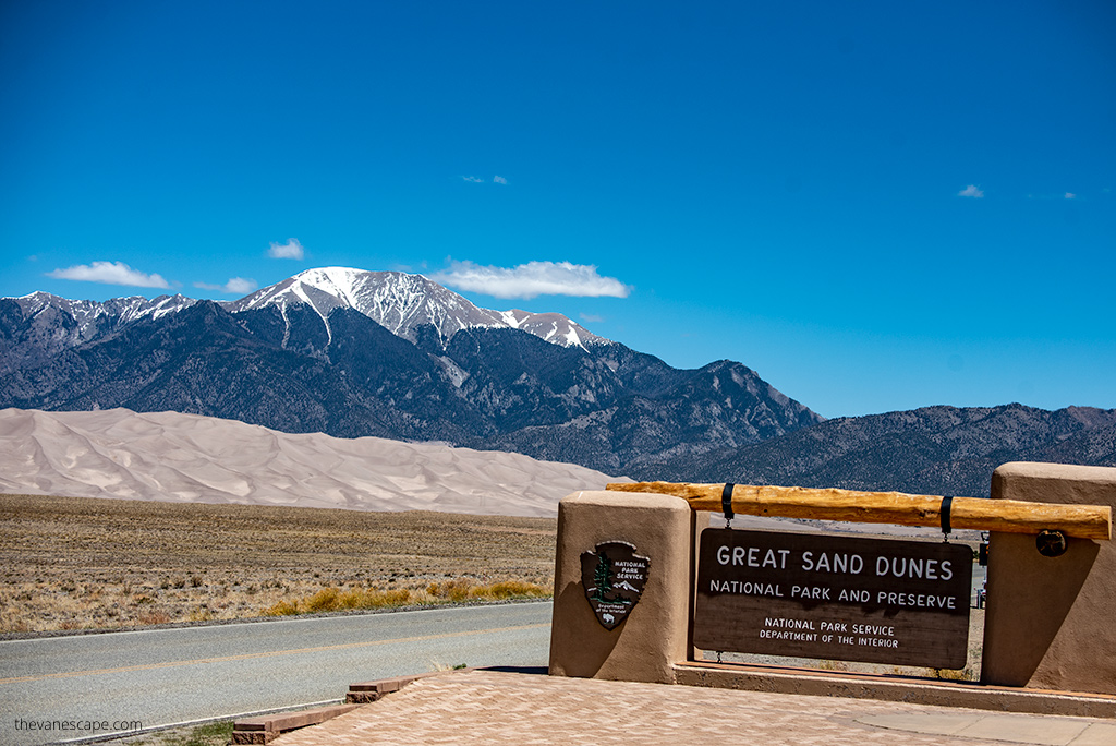 Entrance gate to the Great Sand Dunes National Park with dunes and mountains in the backdrop.