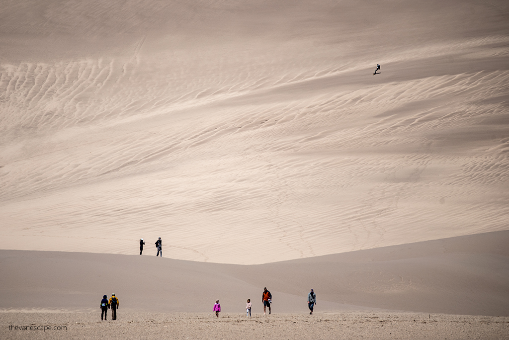 People hiking on dunes.