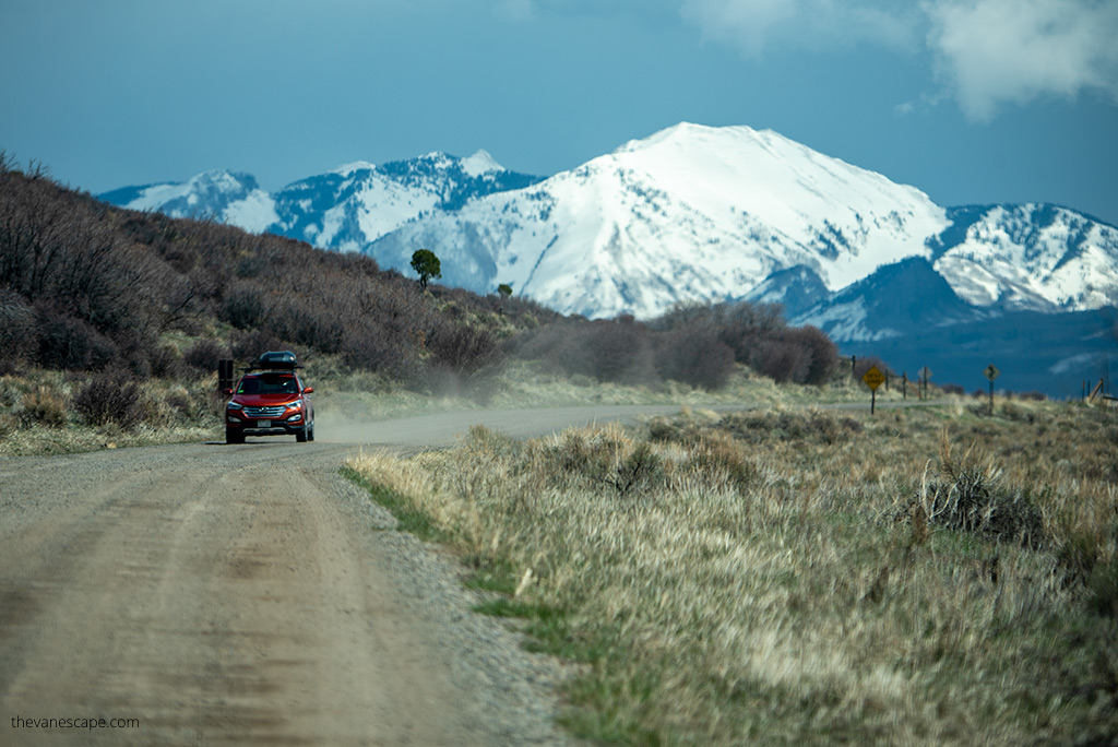 red car on the gravel rad to the park with mountain view in the backdrop.