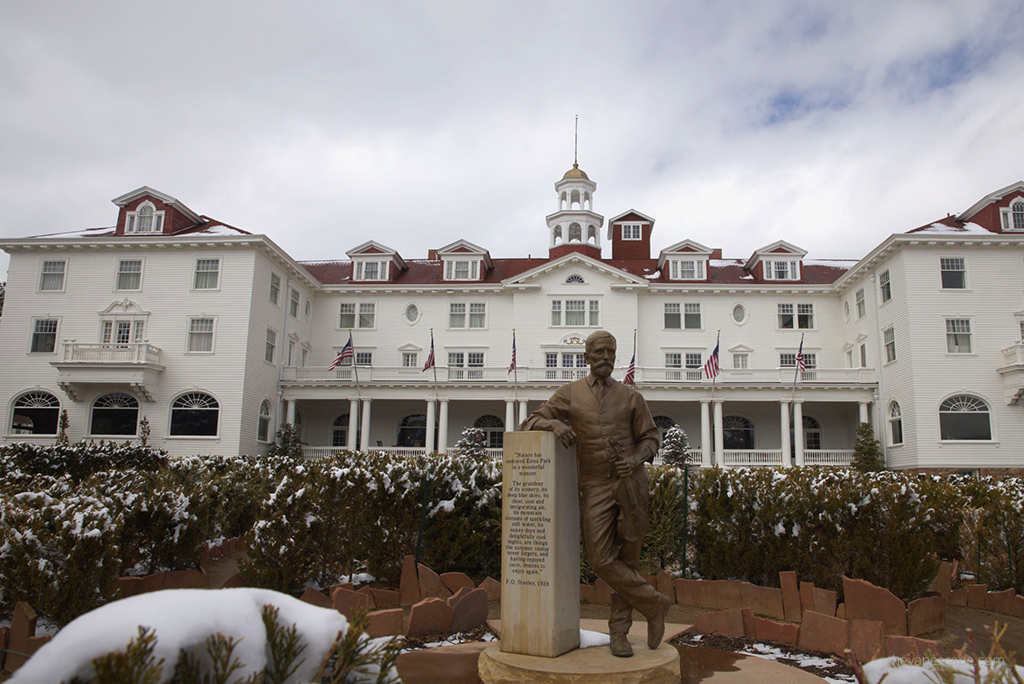A view from the outside of the front wall of the Stanley Hotel with the famous Stanley sculpture standing in front of it.