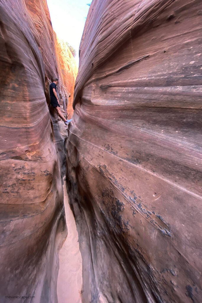 Young men trying to squeezes through Zebra Slot Canyon.
