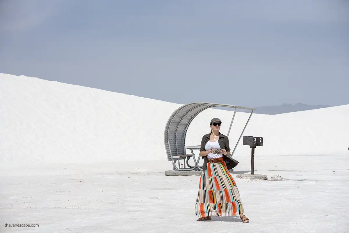 Agnes Stabinska, the author and co-owner of the best USA road trips blog is in orange skirt, sunglasses and hat taking pictures of white dunes. 