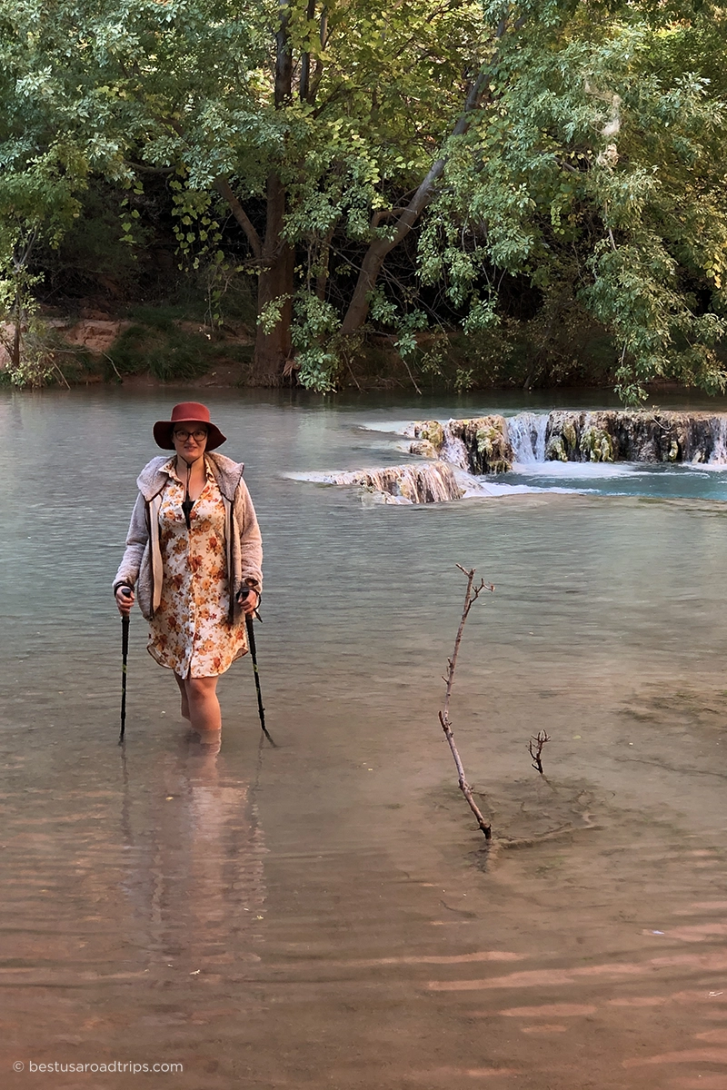 Agnes Stabinska crossing Havasu Creek during the hike to Beaver Falls, standing in the water and using trekking poles for balance.