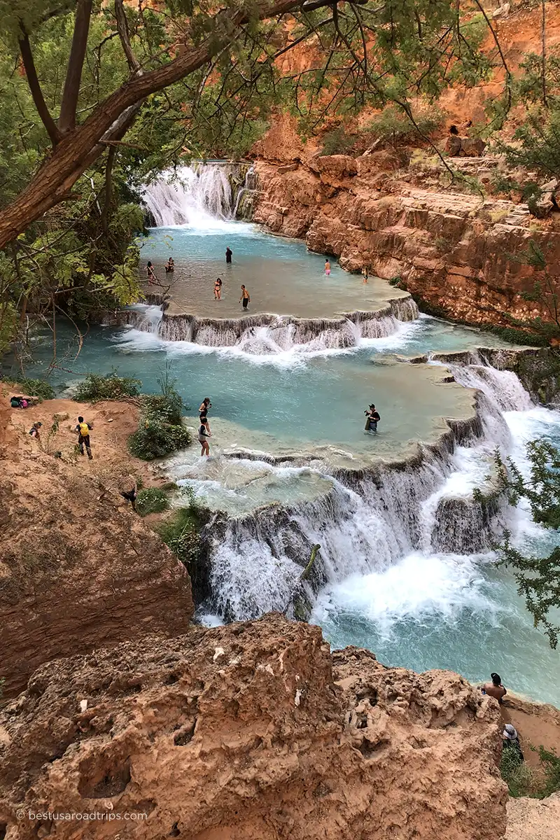People wading, swimming, and taking photos at the cascading pools of Beaver Falls.